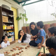 A moment of deep engagement during our sustainable marketplaces project. Facilitators and children discuss ideas, working with miniature bricks to reimagine a community space.