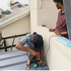 Our team at work installing a puff sheet roof. Safety and precision are paramount as we drill and fasten the panels, ensuring a secure and durable extension for this villa.