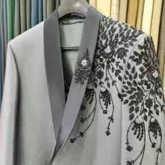 A close-up of the finished embroidery on the grey designer suit, showing the detailed beadwork on the lapel.