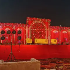 For a bold and royal wedding theme, I design grand stages like this one. It features a rich red floral backdrop with a heart motif, bright yellow velvet sofas for the couple, and dramatic lighting to create a memorable focal point.