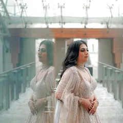 An artistic shot of the bride on her engagement day, using reflections to create a dreamy and contemplative portrait. This highlights her stunning lehenga and the beautiful ambiance of the venue.