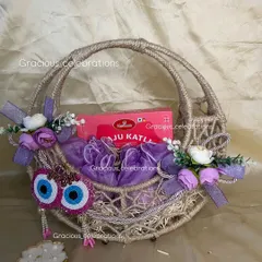 This purple-themed Diwali hamper is all about spreading joy. The jute basket is filled with a box of Kaju Katli and other surprises, decorated with floral accents and evil eye hangings.
