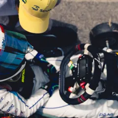 An overhead view of a driver in the cockpit, receiving final instructions from a coach.