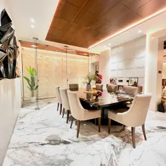 In this dining room, we created a sense of drama and elegance. The design features a stunning wooden ceiling detail that draws the eye, casting a warm glow over the custom black marble dining table and plush, neutral-toned chairs.