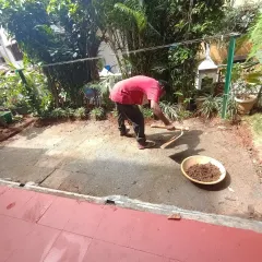 My team member is leveling the soil in a garden space, preparing it for the next stage of the installation process.