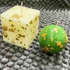 A little gold goes a long way. This minimalist set features a square cube candle and a green sphere candle, both decorated with elegant gold flakes.