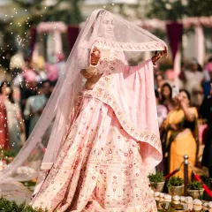 A bride's walk towards her future is a story in itself. Archana, a vision in pink, floats down the aisle under a shower of petals, her grace and beauty captivating everyone, especially the groom waiting for her.