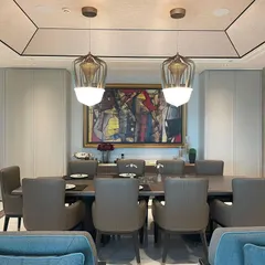 The dining area in the DLF Camellias apartment is an intimate space for family meals. A bold piece of abstract art provides a focal point, while elegant pendant lights and comfortable seating create a warm and inviting ambiance.