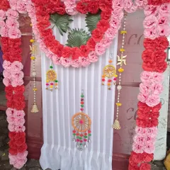 This backdrop for Ganesh Chaturthi shows how I can incorporate specific spiritual symbols into the design. It features a heart-shaped floral arrangement and hanging Swastik symbols, framed by red and pink artificial carnations.