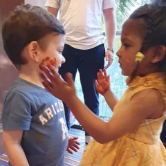 Playdates are all about connection and fun. Here, one child is gently applying face paint to her friend, sharing a sweet and messy moment.