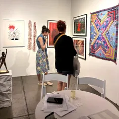 Visitors at our booth at the Seattle Art Fair. The display includes a mix of paintings, textile art by the Siddi Quilters, and sculptures, offering a snapshot of contemporary South Asian art.