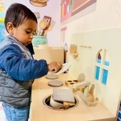 A little chef in the making! Our play kitchen is equipped with wooden toys and a mini stove, perfect for toddlers to practice their cooking skills.