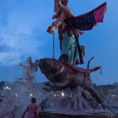 An unusual Ganesha idol riding a mouse is immersed in the water, showcasing the creative and varied iconography of the festival.