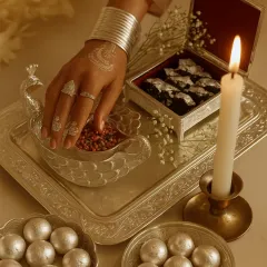 A table setting that glows with timeless elegance. This arrangement of handcrafted silverware, featuring a peacock-motif bowl and pearl-like sweets, shows how tradition and beauty can create moments of pure luxury.