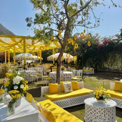 White latticework seating with bright yellow cushions creates a fresh and modern look for this sunny outdoor haldi celebration.