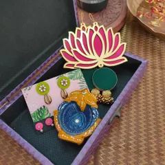 An affordable and beautiful Diwali gift box. This hamper includes a hand-painted diya, two pairs of earrings, and a decorative lotus wall hanging.