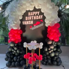 A high-speed race car themed birthday party. This decoration features a striking black, red, and white balloon arch over a custom backdrop with a Formula 1 car, perfect for any young racing fan.