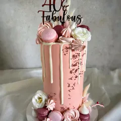 A rose gold beauty for a 40th birthday. This extra-tall 10-inch cake is adorned with a white chocolate drip, macarons, meringues, and flowers for a truly fabulous look.