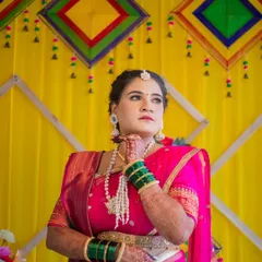A thoughtful and elegant portrait of a bride in a vibrant pink saree. Posed against a colorful yellow backdrop, this shot captures a moment of quiet contemplation amidst the wedding festivities.