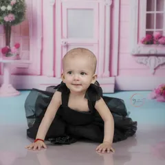 A happy crawling pose from this little girl in her chic black dress. Her smile lights up the entire pink-themed set.