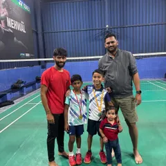Coaches and students celebrating together. Two of our young medalists stand with their coach and a younger sibling, showing the family-friendly atmosphere at our academy.