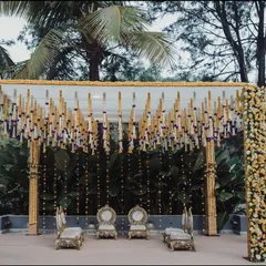 A closer look at a beautiful mandap designed for an outdoor ceremony. The structure is decorated with columns of yellow and white flowers, with hanging floral tassels and strings of lights creating a delicate and festive canopy.