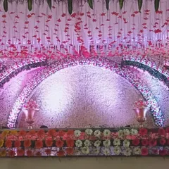 This grand reception stage features a multi-arched design covered in shimmering material and accented with hanging floral arrangements, creating a sense of depth and opulence.