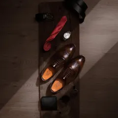 A top-down flat lay of men's formal accessories, with the leather shoes as the centerpiece. This type of shot is great for storytelling, suggesting a complete, sophisticated look for the modern gentleman.