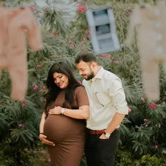 A happy couple moment during their outdoor pregnancy announcement shoot. The props in the background add a charming, rustic feel to the celebration.