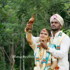 A candid outdoor shot of a newly married couple. The bride's makeup is fresh and natural, designed to last through the entire wedding day, from the ceremony to the outdoor photoshoot.