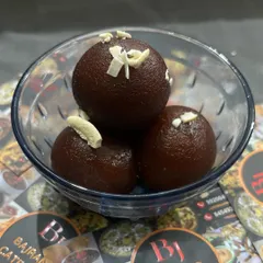 Soft, melt-in-your-mouth gulab jamuns, garnished with almond slivers. I prepare these using a traditional recipe to ensure authentic taste for your festive events.