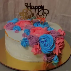 A vibrant and joyful cake featuring a cascade of multi-colored buttercream flowers. The combination of pink, purple, and blue makes this a festive choice for a happy birthday.