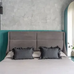 For one of the matriarchs' rooms, I juxtaposed a rugged concrete texture wall with vibrant teal details. The arched dressing mirror and upholstered headboard soften the industrial feel.