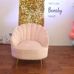 The perfect seat for the mama-to-be! A plush, pink seashell armchair set against a custom backdrop with a gold sequin panel and the theme "We Can Bearly Wait".