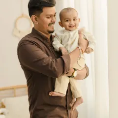 A heartwarming father and son photo. The father holds his laughing baby, capturing a moment of pure joy and connection between them.