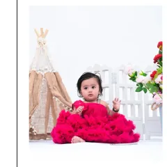 A sweet vertical portrait of the baby girl in her fluffy pink dress. The minimalist white background makes her and the colorful dress pop, highlighting her adorable features.
