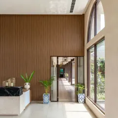 Natural light floods the reception area, highlighting the height of the space and creating a connection to the outdoor courtyards.