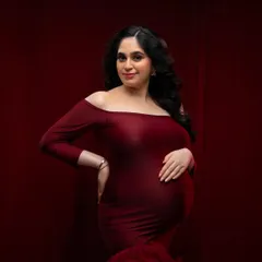 A closer look at the details of this beautiful red gown. The off-the-shoulder neckline and soft fabric beautifully frame the mother's glowing face and baby bump.