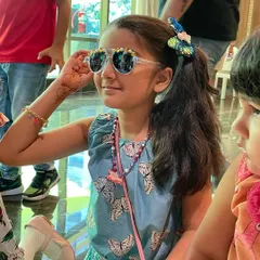 A young guest showing off her fabulous, custom decorated sunglasses. This activity lets kids express their unique style with beads, charms, and all things sparkly.