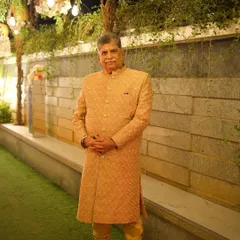 A full-length view of the golden-beige bandhgala, worn as a sherwani. Paired with a matching churidar, this is a timeless and sophisticated outfit for any wedding celebration.