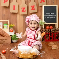 A tiny chef with a very happy, frosting-covered smile. This bakery-themed cake smash is a wonderfully creative way to celebrate a first birthday, complete with a chef's hat and apron.