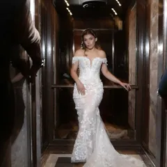 A dramatic entrance for the white wedding. This full-length shot in the elevator captures the grandeur of her dress and the elegance of her bridal hair and makeup.