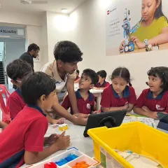 An instructor guides a group of Vidyashilp Academy students through a coding exercise on a tablet. Our after-school programs are designed to be collaborative and highly engaging.