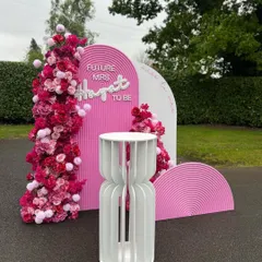 A fun and vibrant bachelorette party backdrop inspired by the popular Barbie theme. This setup includes custom pink arched panels, floral arrangements, and a 'Future Mrs' neon sign for the bride-to-be.