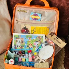 An open view of my kids' suitcase hamper for Rakhi. It's packed with engaging activities like a wooden puzzle, a paint-your-own craft set, and other fun toys.