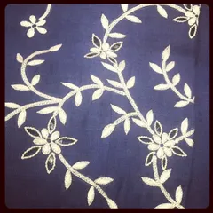 Even simple threadwork can be incredibly elegant. This photo shows a delicate vine pattern created with white and gold thread on a deep blue fabric, perfect for a subtle yet sophisticated design.
