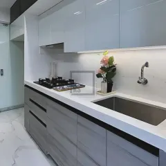 In this monochrome kitchen, we paired sleek white countertops with a built-in hob and sink for a clean, continuous workspace. The combination of handleless upper cabinets and drawers below keeps the look minimalist and modern.