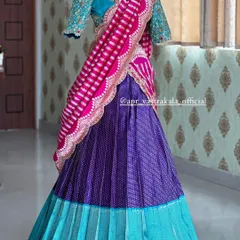 This bridal half-saree set is a masterpiece of color and texture. The design combines a pleated turquoise and purple brocade skirt with a heavily embroidered turquoise blouse and a contrasting striped pink dupatta for a bold, modern bridal look.