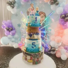 A spectacular multi-tiered cake with a Frozen theme, complete with Anna and Elsa toppers and light-up butterfly wings. The bottom tier can be customized with your child's photos for a personal touch.