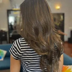 A back view of this stunning balayage, showing how the light caramel tones are blended seamlessly into her natural brown base for a soft, dimensional look.